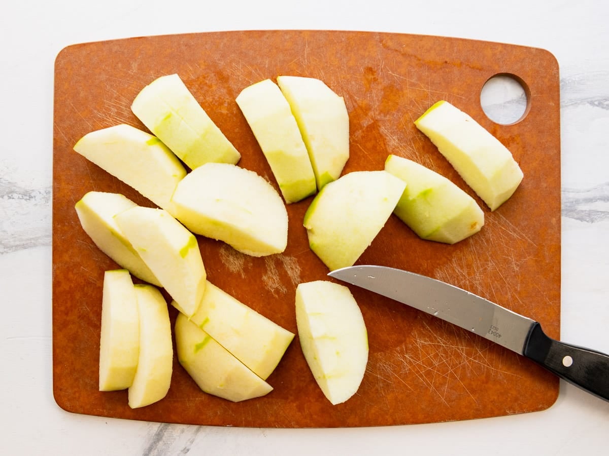 Peeled and sliced Granny Smith apples on a cutting board.