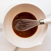 Whisking together the brown sugar and butter sauce mixture in a bowl.