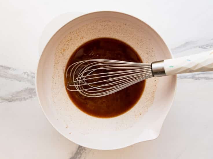 Whisking together the brown sugar and butter sauce mixture in a bowl.