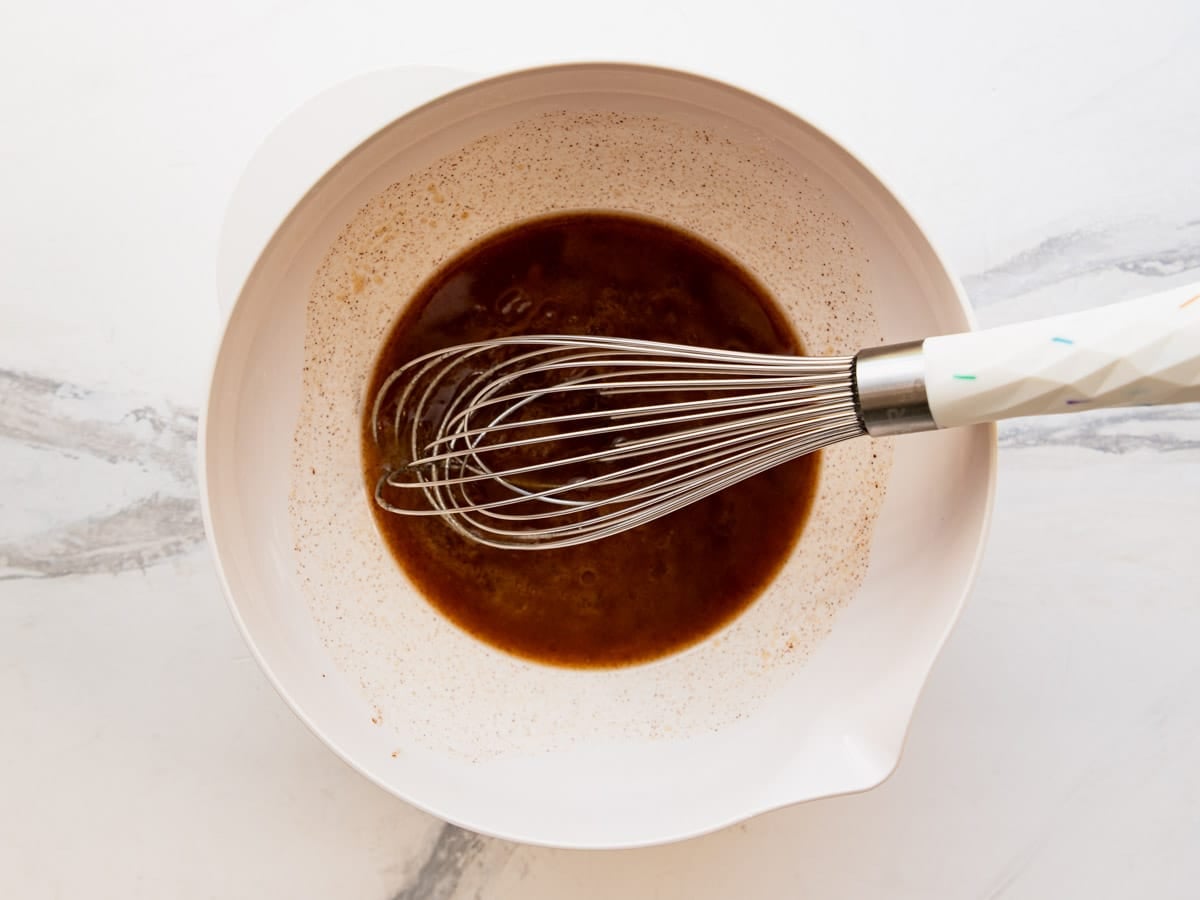 Whisking together the brown sugar and butter sauce mixture in a bowl.