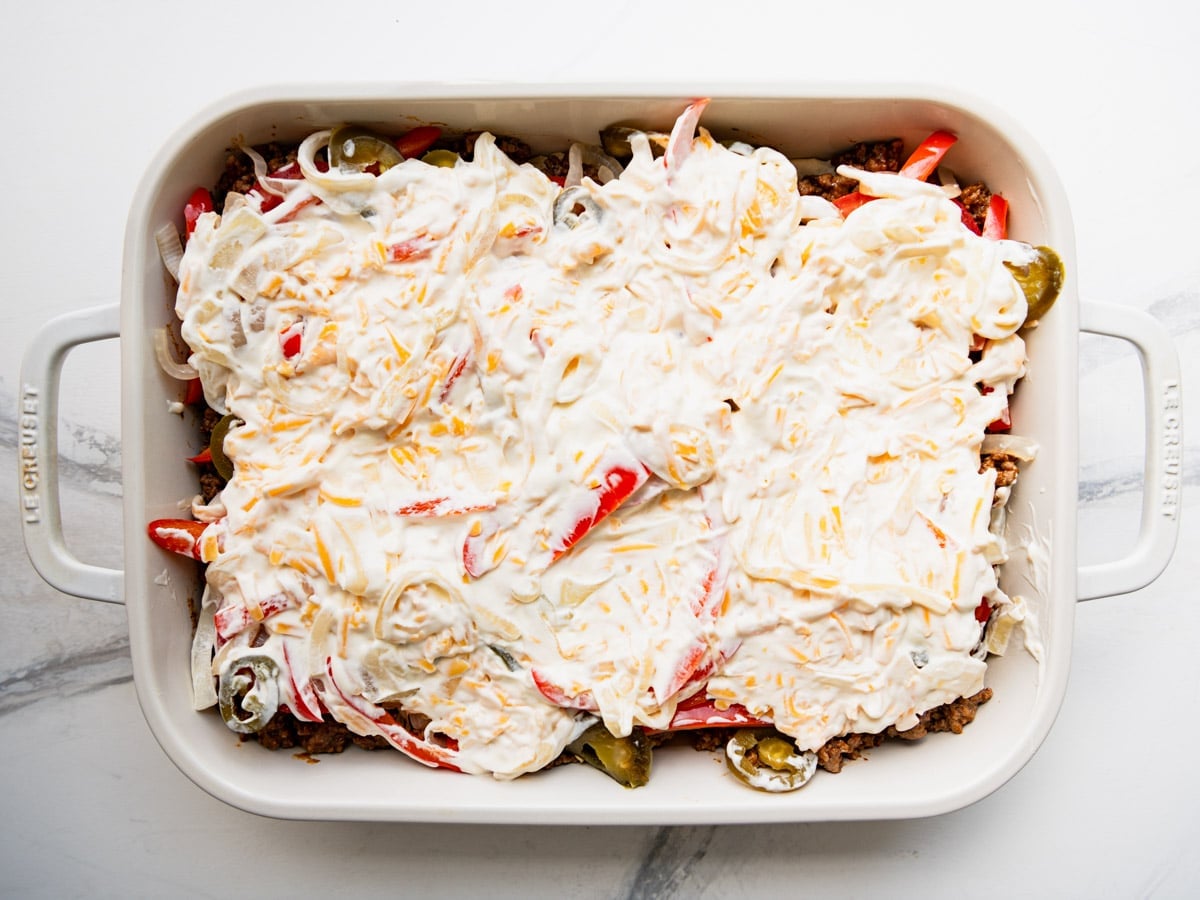 Spreading the creamy layer on top of the vegetables.