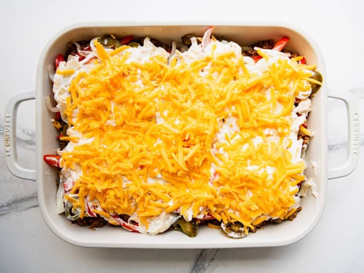 Adding the cheese to the top of a John Wayne casserole before it goes in the oven.