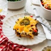 Horizontal side shot of a slice of John Wayne casserole on a white plate.