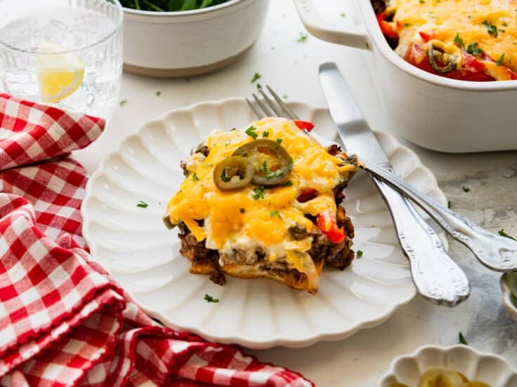 Horizontal side shot of a slice of John Wayne casserole on a white plate.