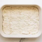 Biscuit dough spread in the bottom of the baking dish.
