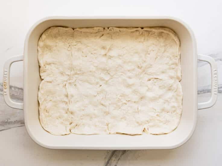 Biscuit dough spread in the bottom of the baking dish.