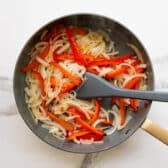 Sauteing peppers and onions in a skillet.