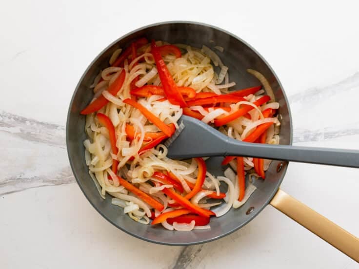 Sauteing peppers and onions in a skillet.
