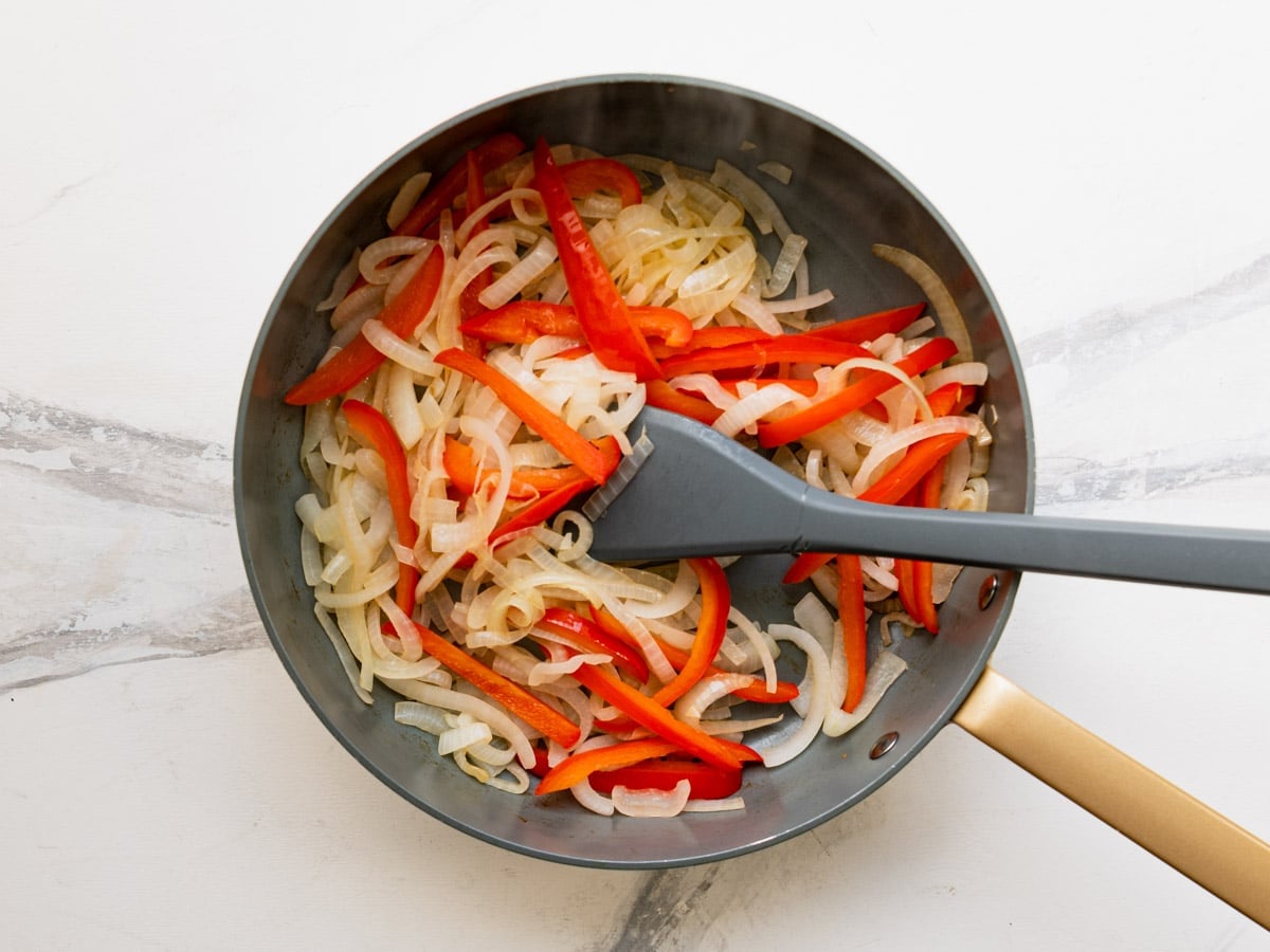 Sauteing peppers and onions in a skillet.
