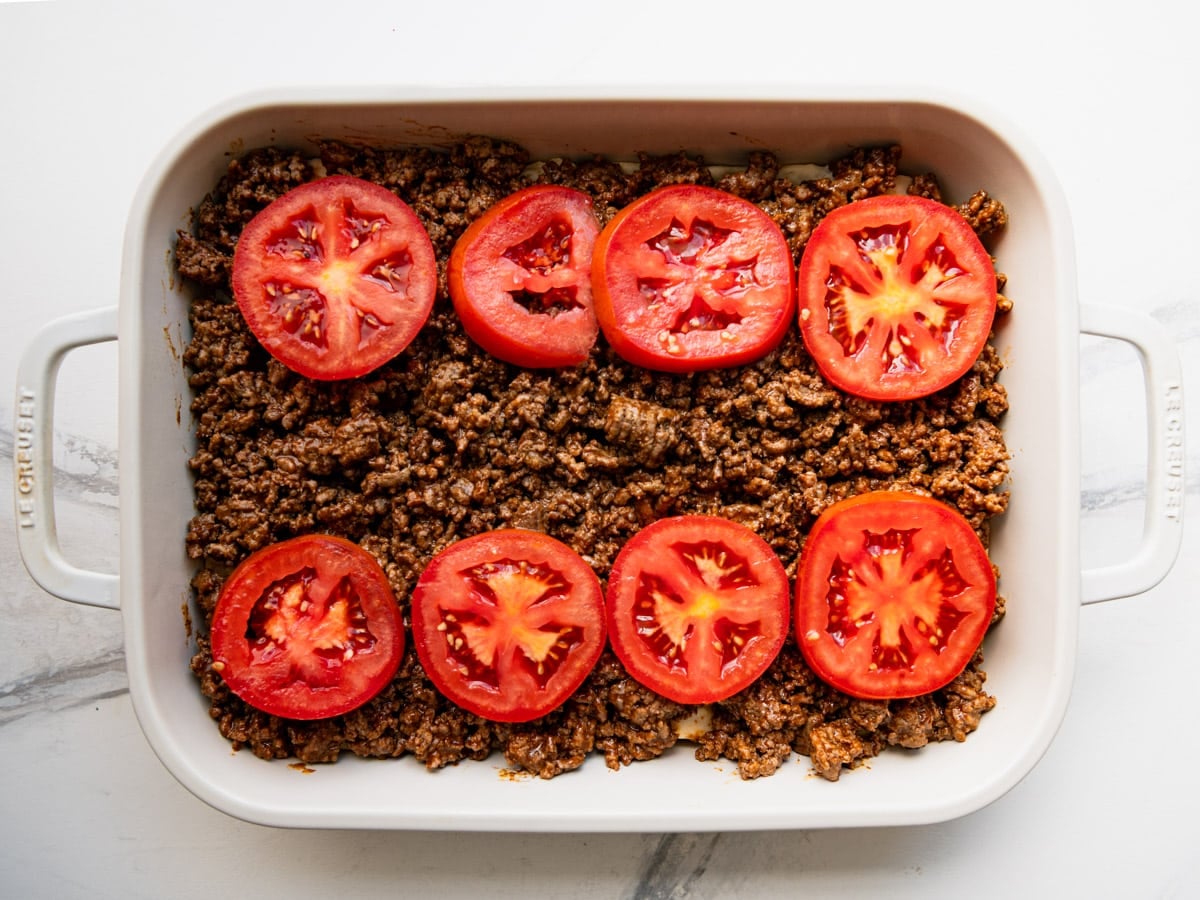 A layer of sliced tomatoes on top of the ground beef.