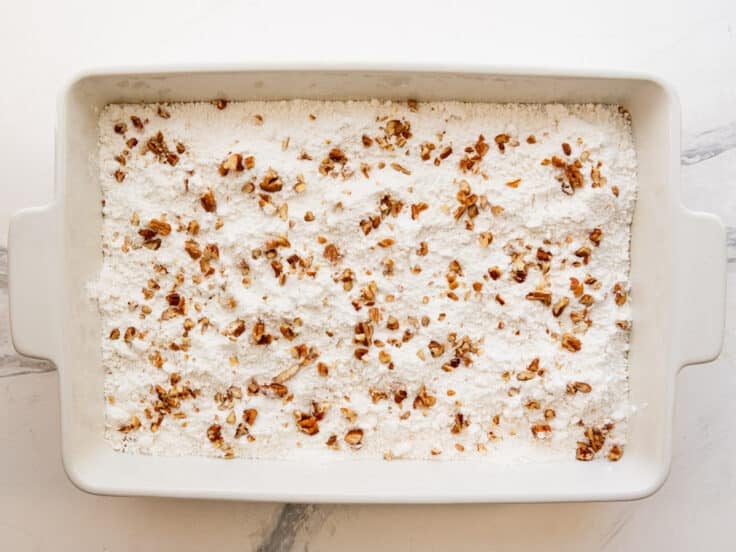 Sprinkling pecans on top of the cake mix.