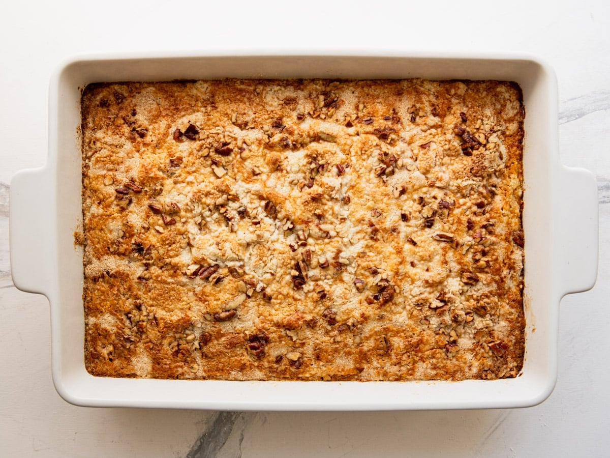 Horizontal overhead image of a white baking dish full of baked pumpkin dump cake.
