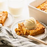 Horizontal side shot of a slice of pumpkin dump cake on a plate with vanilla ice cream on top.