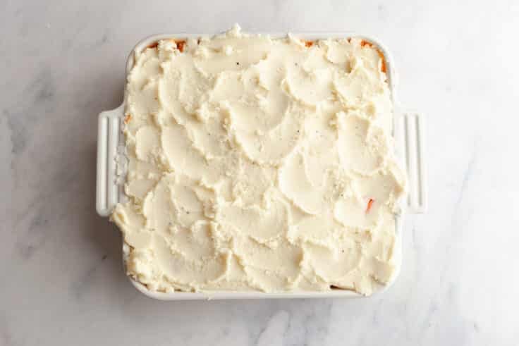 Spreading the mashed potatoes on top of a shepherd's pie.