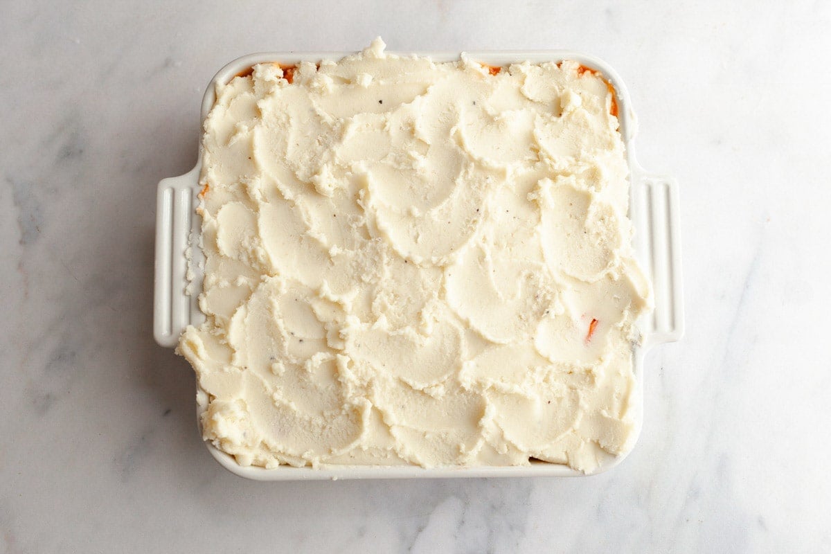 Spreading the mashed potatoes on top of a shepherd's pie.