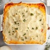 Horizontal overhead image of a baked shepherd's pie in a white dish.