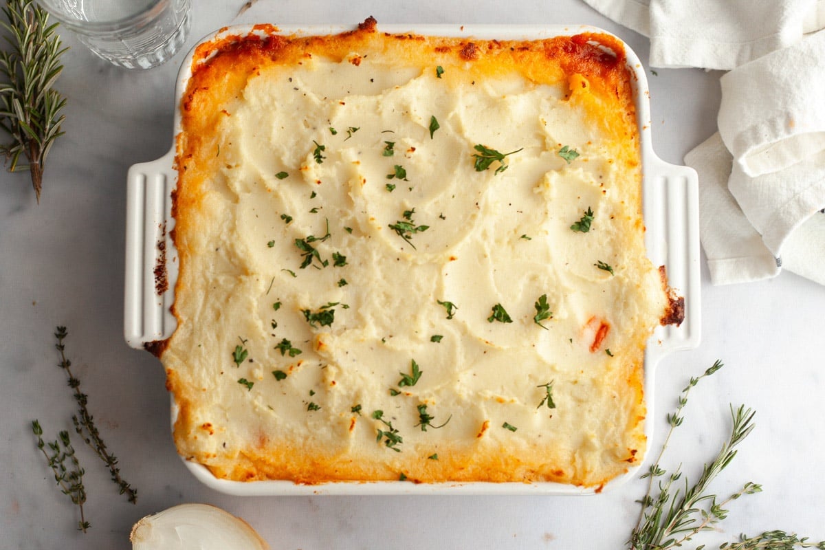 Horizontal overhead image of a baked shepherd's pie in a white dish.