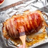 Basting the bacon wrapped meatloaf with more glaze.