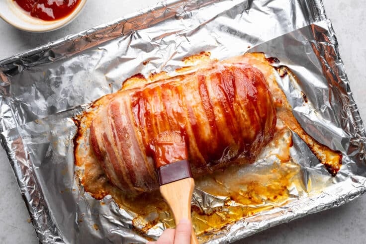 Basting the bacon wrapped meatloaf with more glaze.